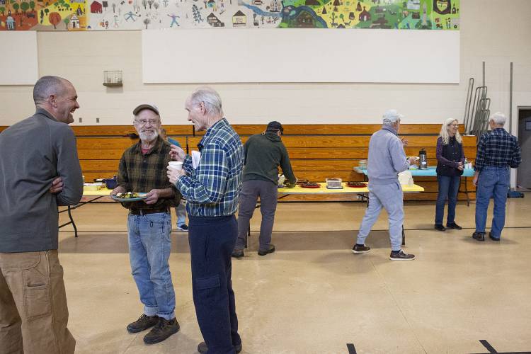 Jim Masland, center, of Thetford, Vt., talks to Jim Kearns, right, of Sharon, Vt., during the Sharon Skill Swap potluck at Sharon Elementary School in Sharon, Vt., on Saturday, Feb. 10, 2024. The event was organized in response to feedback from a series of town-wide meetings where residents said they wanted more opportunities to build community in town. (Valley News / Report For America - Alex Driehaus) Copyright Valley News. May not be reprinted or used online without permission. Send requests to permission@vnews.com.