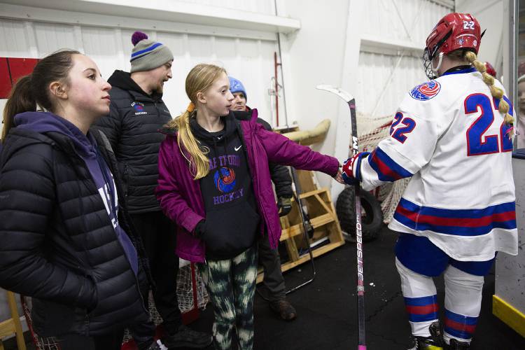 Aubree Gramling, 11, center, congratulates Hartford players as they leave the ice while standing with her friend Maria Chaput, 12, left, and her father Hartford goalie coach Jason Gramling during a VPA D-II girls hockey quarterfinal game against Stowe High School at Wendell A. Barwood Arena in White River Junction, Vt., on Wednesday, Feb. 28, 2024. (Valley News / Report For America - Alex Driehaus) Copyright Valley News. May not be reprinted or used online without permission. Send requests to permission@vnews.com.
