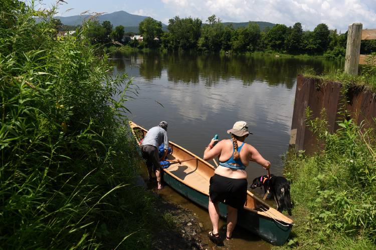 Elizabeth Towle, of Bradford, Vt., leads her dog Ruby to the canoe she is paddling on the Connecticut River with friend Lynne Newton, of Woodstock, Vt., on Wednesday, July 5, 2023, in Cornish, N.H. The two met as children when they were at an Upper Valley summer camp. They were staying at Wilgus State Park in Weathersfield, Vt., and are paddling from Cornish to their campsite. Newton said they were 
