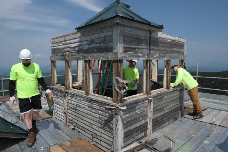 Alex Kershaw, left, Kyle Hathaway, middle, and Mike Morrison, right, of Valley Restoration, work on the demolition and rebuilding of the Mount Cardigan fire tower cab in Orange, N.H., on Thursday, Aug. 10, 2023. The tower was originally completed in 1924 and has received upgrades to the steel tower and two cab replacements in its 100 years. “If we were going to do this in your back yard, it’d be a week project,” said Steve Hogan, project manager for general contractor Careno Construction. Because of weather delays, the difficulty of working in a remote location, and the concurrent cab replacement on Mount Belknap, the project is in its fourth month. (Valley News - James M. Patterson) Copyright Valley News. May not be reprinted or used online without permission. Send requests to permission@vnews.com.