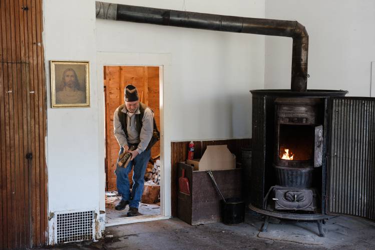 Jim Noel, of Royalton, builds a fire to warm the classroom of the Octagon building while cleaning during a work day for the community church in East Bethel, Vt., on Saturday, Feb. 24, 2024. “I’m not a church goer,” said Noel, but he has an interest in the history of the organization and surrounding area and wants to be of service. (Valley News - James M. Patterson) Copyright Valley News. May not be reprinted or used online without permission. Send requests to permission@vnews.com.