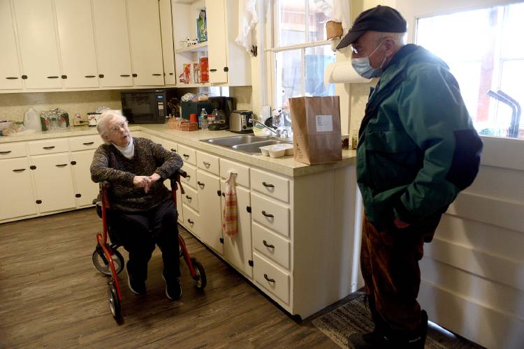 Meals on Wheels volunteer Al Pristaw, of Woodstock, Vt., chats with Joyce Phillips while delivering her pork tenderloin lunch on Thursday, March 24, 2022. Last summer, Phillips moved in with her son in Bridgewater, Vt. 