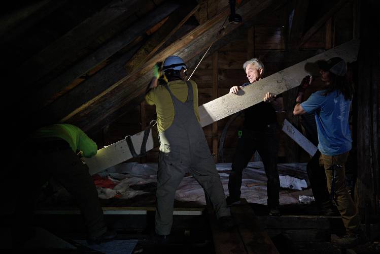 Jan Lewandoski, of Stannard, second from right, helps lift a secondary rafter into place with, from left, Adam King, of Roxbury, Mike Cotroneo, of Morrisville, and Joe Cotter, of Northfield, right, to reinforce a truss that supports the back of the First Universalist Church and Society’s steeple in Barnard, Vt., on Thursday, June 22, 2023. “A lot of church king post truss systems would have had this built in originally,” said King. “For whatever reason, the framer of this one decided to not double the rafters.” The rafter is made of spruce cut from Lewandoski’s property. (Valley News - James M. Patterson) Copyright Valley News. May not be reprinted or used online without permission. Send requests to permission@vnews.com.