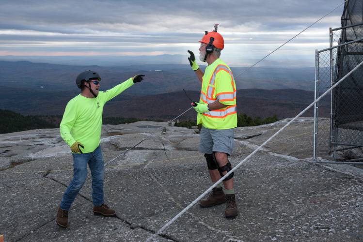 Over the noise of a generator, Valley Restoration project manager Bob McGlothin, left, and Mark McAfee, of North American Helicopters discuss plans for an incoming flight of supplies the fire tower cab replacement on Mount Cardigan in Orange, N.H., on Thursday, Oct. 26, 2023. (Valley News - James M. Patterson) Copyright Valley News. May not be reprinted or used online without permission. Send requests to permission@vnews.com.