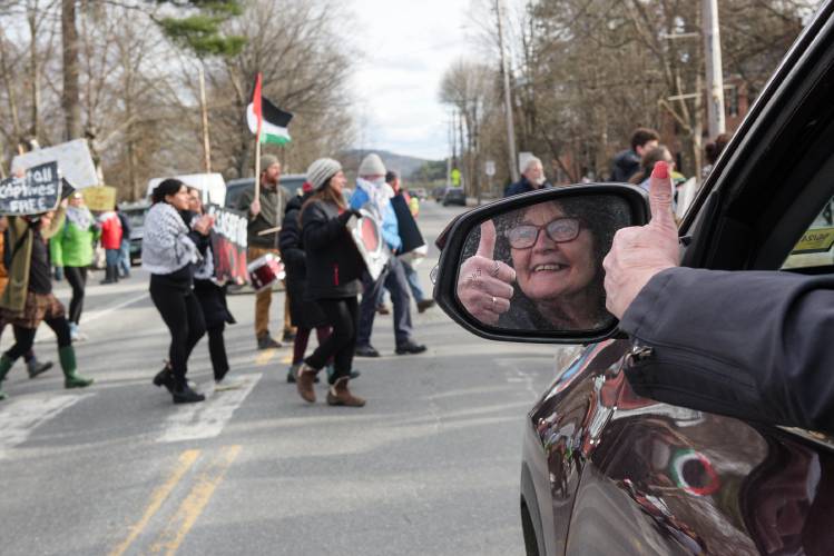 Karen Ness, stops her vehicle to let protesters pass on their march toward the private home in Norwich, Vt., where First Lady Jill Biden attended a fundraising on Tuesday, March 19, 2024. 