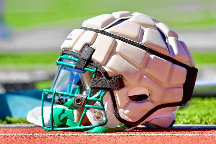 A helmet with a Guardian Cap on it sits on the Memorial Field track during a Dartmouth College football practice on April 8, 2023. This is the first season all Big Green players except quarterbacks and kickers are required to use the Caps, which its manufacturer says reduce impact to the head. (Valley News - Tris Wykes) Copyright Valley News. May not be reprinted or used online without permission. Send requests to permission@vnews.com. 