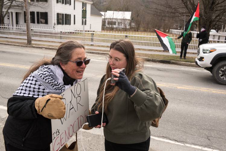 Sabra Ewing, of Vershire, left, speaks with White River Junction activist Ashley Andreas, right, as she records a streaming video for The Robust Opposition during a protest of First Lady Jill Biden's fundraising visit to Norwich, Vt., on Tuesday, March 19, 2024. Ewing said she was invited by Norwich resident Jane Stetson to the fundraiser at her home, but declined and joined the protest instead. 