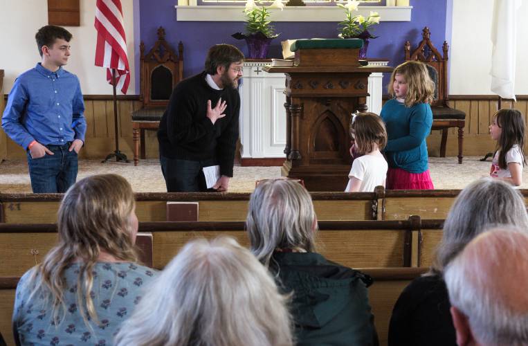 While leading the service, Ben Wolfe, of Tunbridge, second from left, welcomes, from left, Braden White, 12, Brenya Huston, 4, Hailey Williams, 8, and Natalie Post, 5, to the front of the church during Easter service in East Bethel, Vt., on Sunday, March 31, 2024. It was the second service since a new board was formed last December. (Valley News - James M. Patterson) Copyright Valley News. May not be reprinted or used online without permission. Send requests to permission@vnews.com.