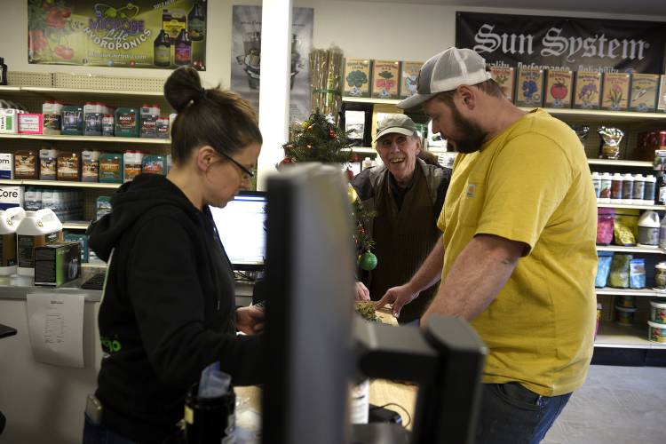 At White River Growpro, co-owner Stephanie Waterman tests cannabis samples from Sean Trombly's plants on Thursday, Dec. 14, 2023. Another licensed cannabis grower, Frank Fetter, of Tunbridge, Vt., talks shop with Trombly while at the store to pick up supplies.  (Valley News - Jennifer Hauck) Copyright Valley News. May not be reprinted or used online without permission. Send requests to permission@vnews.com.