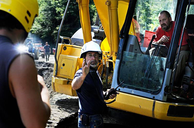 In the aftermath of Tropical Storm Irene, Bethel Fire Chief Dave Aldrighetti, center, talks with an excavator operator who filled a washed-out section of Camp Brook Road to allow a convoy of ATVs to pass on their way to Rochester, Vt., on Aug. 30, 2011. (Valley News - James M. Patterson) Copyright Valley News. May not be reprinted or used online without permission. Send requests to permission@vnews.com.