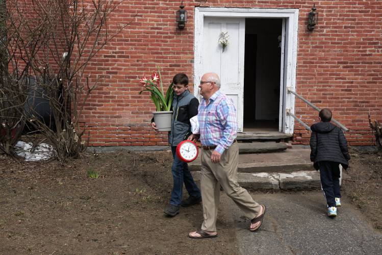 Church Trustee Jerry Barcelow,of South Royalton, middle, departs with his grandson Braden White, left, and a clock used to keep the Easter service on track in East Bethel, Vt., on Sunday, March 31, 2024. McKinley Post, 9, is at right. (Valley News - James M. Patterson) Copyright Valley News. May not be reprinted or used online without permission. Send requests to permission@vnews.com.