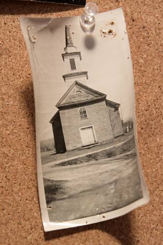 “East Bethel Church, Summer 1949, Before painting,” reads a caption on the back of a photograph of the 1824 building pinned to a bulletin board in its entryway, on Sunday, March 31, 2024. The church underwent a revival in the 1950s under the establishment of the East Bethel Community Association. (Valley News - James M. Patterson) Copyright Valley News. May not be reprinted or used online without permission. Send requests to permission@vnews.com.