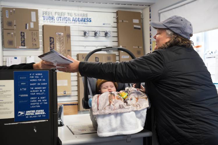 With postal delivery suspended across the Town of Sharon, Vt., Carol Flint, of Newport, with her grandson Callum, picks up her mail in person from a clerk who declined to be identified on Friday, Dec. 8, 2023. 