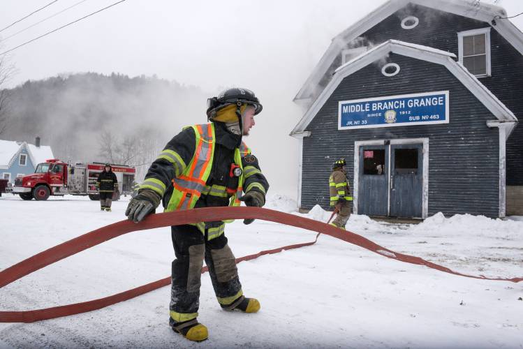 Bethel Firefighter Sonny Snelling lays out hose at the Middle Branch Grange Hall in East Bethel, Vt., during a fire that Bethel Chief David Aldrighetti said likely started when a wood furnace failed on Saturday, Jan. 20, 2024. Fire departments from South Royalton, Randolph Center, East Randolph and Barnard joined the effort to save the building. (Valley News - James M. Patterson) Copyright Valley News. May not be reprinted or used online without permission. Send requests to permission@vnews.com.