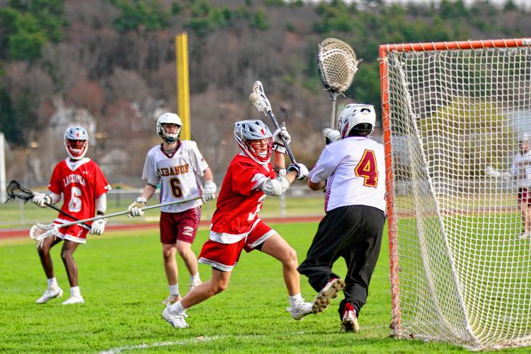 Lebanon High goaltender James Barnett (4) challenges Laconia's Paul Ganchi (3) during the NHIAA Division III teams' meeting on April 17, 2024 at Henry Emerton Field in Lebanon, N.H. Laconia's J.P. Harriman and Lebanon's Miles Saunders look on. Ganchi did not score, but his Sachems won, 8-2. (Valley News - Tris Wykes) Copyright Valley News. May not be reprinted or used online without permission. Send requests to permission@vnews.com. 