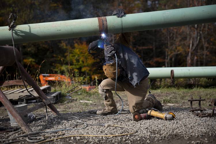 Nick Ross, of Holderness, N.H., welds two sections of steel pipe together at Oak Hill Outdoor Center in Hanover, N.H., on Wednesday, Oct. 25, 2023. A crew from Royalton Trail Works is placing about 22,000 feet of steel and high density polyethylene pipe to use in snowmaking operations along the cross country ski trail. (Valley News / Report For America - Alex Driehaus) Copyright Valley News. May not be reprinted or used online without permission. Send requests to permission@vnews.com.