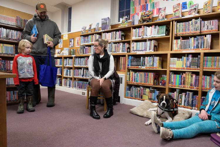 Barrett Bentley, 4, left, and his dad Eric, of Claremont, stop to admire Nala, a therapy dog that Vicki Bonneau, middle, brings to the Fiske Free Library in Claremont, N.H., every other week to read with children on Thursday, Jan. 25, 2024. Bonneau is a para-educator at Maple Avenue Elementary and she and Nala are one of three therapy dog teams that visit the library for the reading sessions. Anastasia Underhill, 10, of Claremont, is at right.  (Valley News - James M. Patterson) Copyright Valley News. May not be reprinted or used online without permission. Send requests to permission@vnews.com.