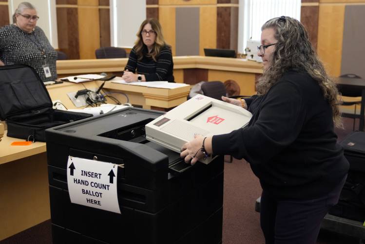 File - Lisa Hultgren, the Derry, N.H. town moderator, loads a vote counting machine into a cart, which stores the paper ballots, while testing vote counting machines before the New Hampshire primary at the Derry Municipal Center, Tuesday, Jan. 16, 2024. (AP Photo/Charles Krupa, File)