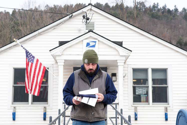 Zach Wood checks his mail after picking it up from the post office in Sharon, Vt., while delivery is suspended on Friday, Dec. 8, 2023. Wood said his grandmother and grandfather were both postmasters and they were able to support their family of 12 kids on their salaries. 