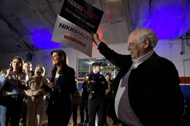 Enoch Stiff, of Ossipee, N.H., holds up a Nikki Haley sign for the candidate while supporters have a photo taken with Haley on Wednesday, Dec. 13, 2023, in Newport, N.H. Stiff said he is a supporter of Haley and was roped into holding the sign for a friend because his friend's arms got tired doing the same at an earlier event. (Valley News - Jennifer Hauck) Copyright Valley News. May not be reprinted or used online without permission. Send requests to permission@vnews.com.