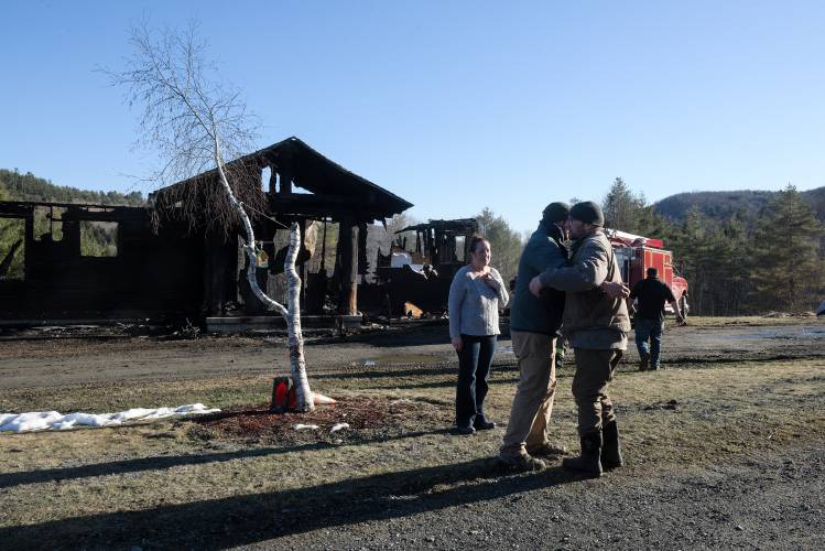 Erica Brinkman, left, looks on as her boyfriend Evan Burnham, second from left, gets a hug from his second cousin Dean Morgan, second from right, outside the remains of his home in Royalton, Vt., on Saturday, March 30, 2024. Royalton Firefighter Larry Stewart returns to his truck at right. Burnham discovered the fire and called the fire department to the Broad Brook Road home he shares with Brinkman at 9:30 a.m. on Saturday. They both escaped uninjured. Fire Chief Paul Brock said that the building was already starting to collapse when he arrived and is a total loss. “Fifteen minutes from the time we were on scene, the house was in the basement,” he said. The fire originated in a utility room, according Burnham, and spread fast through the open floor plan, accelerated by windy conditions. Fire departments from Sharon, Barnard, East Barnard, Tunbridge, Bethel and Hartford provided mutual aid. Burnham said his uncle built the home in 2005, and he bought it eight years ago to keep the property in the family. (Valley News - James M. Patterson) Copyright Valley News. May not be reprinted or used online without permission. Send requests to permission@vnews.com.