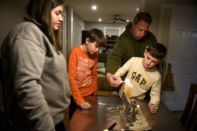 Becca and Aaron Sacks light the candles of their menorah with their sons Judah, 11, and Solomon, 9, at their home in Norwich, Vt., on Tuesday, Dec. 12, 2023. The family is part of the Upper Valley Jewish Community congregation. (Valley News - Jennifer Hauck) Copyright Valley News. May not be reprinted or used online without permission. Send requests to permission@vnews.com.