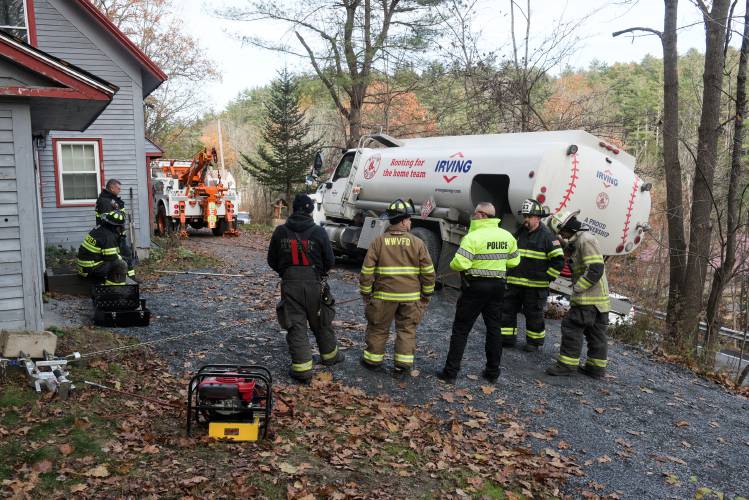 Weathersfield Police Chief Bill Daniels, third from right, talks with firefighters from West Weathersfield and Springfield while waiting for a second recovery truck to arrive and remove an Irving heating oil truck after it got stuck on a soft driveway on a steep bank over Route 131 in West Weathersfield, Vt., on Wednesday, Nov. 8, 2023. (Valley News - James M. Patterson) Copyright Valley News. May not be reprinted or used online without permission. Send requests to permission@vnews.com.