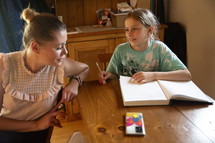 Iryna Burtolik, left, talks to her daughter Anya, 10, as she writes in a journal in Hartland, Vt., on Wednesday, August 9, 2023. Most of Anya’s entries are in Ukrainian and Iryna said she hopes she starts writing more in English, which the families have been learning together through books, movies and talking to their sponsors and neighbors. (Valley News / Report For America - Alex Driehaus) Copyright Valley News. May not be reprinted or used online without permission. Send requests to permission@vnews.com.