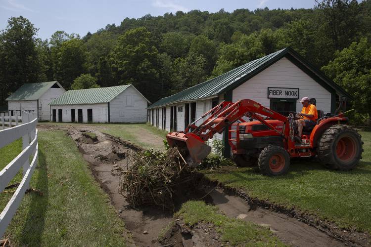 Bob Gray, who manages the maintenance of the fairgrounds, moves debris into a ditch left by floodwater near the sheep barn at the fairgrounds in Tunbridge, Vt., on Thursday, July 13, 2023. “I think we were pretty fortunate,” Gray said of the relatively limited damage. “We’ve got a lot of work to do to bring it back to where it was, but it’s all work that can be done.” (Valley News / Report For America - Alex Driehaus) Copyright Valley News. May not be reprinted or used online without permission. Send requests to permission@vnews.com.
