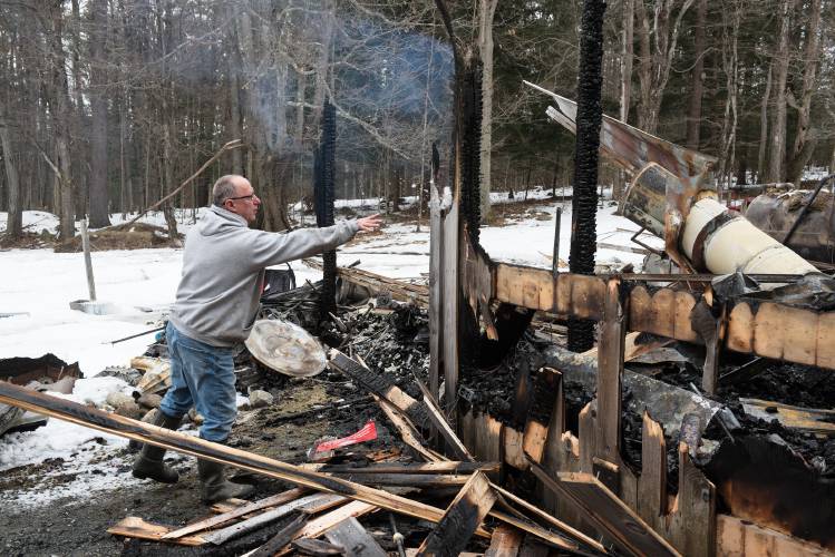 Tom Guillette tosses a handful of snow at a hot spot before returning with a bucket of water to put it out in the remains of his workshop in Canaan, N.H., on Thursday, Feb. 22, 2024, after it was destroyed by fire Wednesday night. Guillette credits the six responding fire departments, Canaan, Lebanon, Enfield, Hanover, Lyme and Dorchester, for their work in containing the fire to save his sugar house, which sits just feet away, and prevent flames spreading to his nearby home. “The response was absolutely amazing,” he said. No one was injured in the fire.

Tom Guillette and his wife Julie sat watching the news at about 7 p.m. on Wednesday Feb. 21, 2024, when they noticed their whole back yard lit up. Two hours earlier he had finished cleaning up and cooling down the crucible in his nearby foundry shop where he melts aluminum to cast cemetery markers. Looking out the window, they saw that the bright light in the yard was caused by the shop burning. 

“It’s a huge financial hit,” to his supplemental income said Guillette, who retired six years ago from his position as facilities manager at the Hanover Co-op. With orders for 12,000 markers on his books, he has had to send customers to a competitor. 

The aluminum that he buys at Massachusetts junk yard sometimes has the flammable metal magnesium mixed in with it. Guillette separates out the magnesium to return to the scrap dealer, and a box of that metal stored in a corner of the shop complicated the efforts to extinguish the fire, he said, because it can burn more intensely when contacted by water. The fire was out and the trucks gone by about 11:30 p.m., he said.

“It’s just something you never expect,” said Guillette. “This is the first fire I’ve been associated with that was close, and I could see how serious it is.”

Founded by Joseph DeFontes in 1953, Guillette bought the business in the 1990s when transitioning out of his career as an engineer at Timken Aerospace. Some of the original equipment destroyed in the fire was made by DeFontes. Guillette said the building was insured for the value of the structure’s replacement. “It’s been a long road, but I learned a lot in that building there and was still learning,” he said. (Valley News - James M. Patterson) Copyright Valley News. May not be reprinted or used online without permission. Send requests to permission@vnews.com.