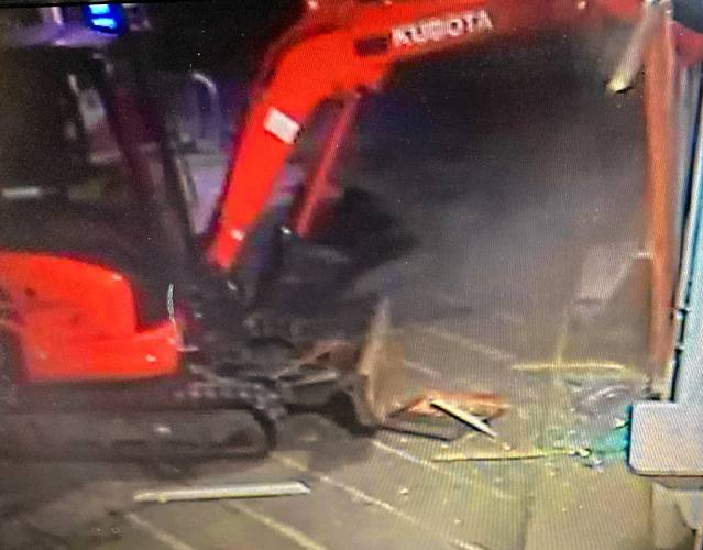 A survellance camera shows a person using a Kubota excavator to open up the front wall of a convenience store in Weathersfield, Vt., on July 16, 2023, to remove the store's ATM. (Courtesy Vermont State Police) 
