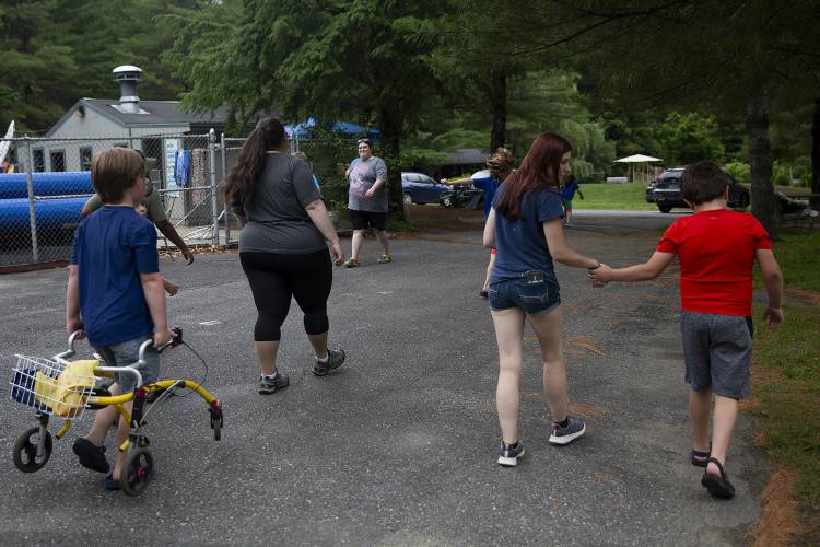 George Busnach, 10, right, of Thetford, Vt., holds hands with his one-on-one aide Kayla Woodman, of Windsor, Vt., as they walk between activities during the Special Needs Support Center’s Camp Aspire at Storrs Pond Recreation Area in Hanover, N.H., on Thursday, June 29, 2023. (Valley News / Report For America - Alex Driehaus) Copyright Valley News. May not be reprinted or used online without permission. Send requests to permission@vnews.com.