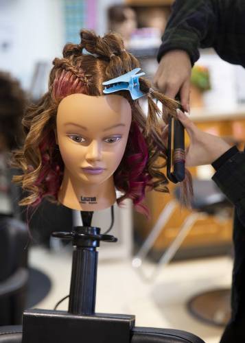 Woodsville senior Skylar Welch, 17, of Woodsville, N.H., curls a mannequin’s hair during a cosmetology class at River Bend Career and Technical Center in Bradford, Vt., on Wednesday, Dec. 6, 2023. Students in the program learn to cut, style and dye hair, as well as other services like manicures and facials. (Valley News / Report For America - Alex Driehaus) Copyright Valley News. May not be reprinted or used online without permission. Send requests to permission@vnews.com.