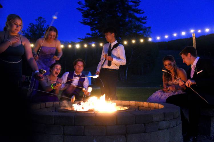 At Mascoma Valley Regional High School's prom, Josh Park roasts marshmallows with friends Hailey Miller, left, Sierra Gianini, Alanna Cilbrith, Logan Gilmore, Izzy Adams and Asa Michetti on Saturday, May 13, 2023, in Danbury, N.H. Park is home-schooled but takes a couple of classes at Mascoma. He also competes on the school track team with Cilbrith, Gilmore, Michetti and Adams. Park attended the prom carrying a five-pound battery pack to power a mechanical pump for his heart. His parents remained nearby in the parking lot in case he had any problems. In March, Park, then 16 was diagnosed with heart failure. (Valley News - Jennifer Hauck) Copyright Valley News. May not be reprinted or used online without permission. Send requests to permission@vnews.com.