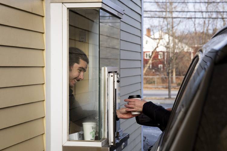 Barista James Pardo hands a coffee through the window at Lucky’s Drive Thru in Lebanon, N.H., on Friday, Jan. 5, 2024. The coffee shop, which filled the vacant space left after the closure of Jake's Coffee Company on Mechanic Street, will be open on Fridays and Saturdays from 7 a.m to 2 p.m., with plans to expand their hours after hiring more staff members. (Valley News / Report For America - Alex Driehaus) Copyright Valley News. May not be reprinted or used online without permission. Send requests to permission@vnews.com.