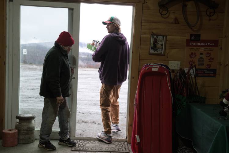 James Pike, of Sunapee, right, leaves the Patch Orchards store with an armful of hard cider he bought from Barbara Patch, left, on Thursday, Dec. 28, 2023. Patch said that losses to her apple crop would have been worse, but some frost damaged apples from a freeze last May were able to be used for cider. (Valley News - James M. Patterson) Copyright Valley News. May not be reprinted or used online without permission. Send requests to permission@vnews.com.