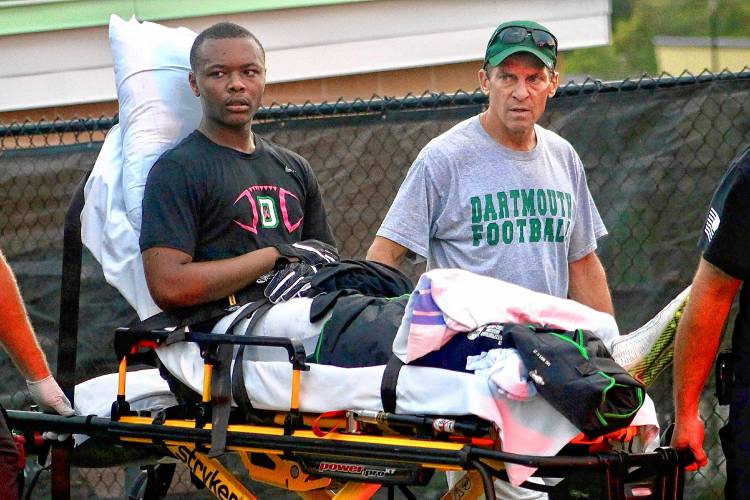 Dartmouth College head football coach Buddy Teevens walks off the Blackman Fields with player Darryl Mobley after the receiver broke his leg during practice on Sept. 21, 2017, in Hanover, N.H.