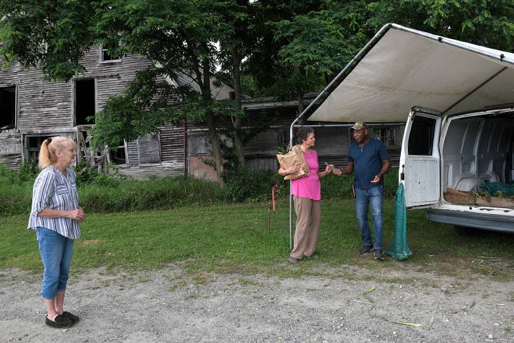Lauren McClure, of Hartland, middle, buys a bag of MacLennan Farm sweet corn from George Smith, 62, of Jamaica, right, as Candace Jones, of Hartland waits her turn at left in Windsor, Vt., on Monday, July 31, 2023. 