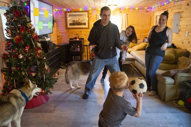 Clockwise from bottom, Joe Mispel, 4, winds up to throw a ball while playing with his father Nathan, sister Faith, 13, and mother Casey in their living room in Bridgewater, Vt., on Wednesday, Dec. 20, 2023. The Mispels’ home flooded in July, and with the help of family and community members they were able to rebuild and move back in 41 days after receiving disaster assistance from FEMA. “It’s been quite the journey,” Nathan Mispel said. “We have a lot to be grateful for this Christmas.” (Valley News / Report For America - Alex Driehaus) Copyright Valley News. May not be reprinted or used online without permission. Send requests to permission@vnews.com.