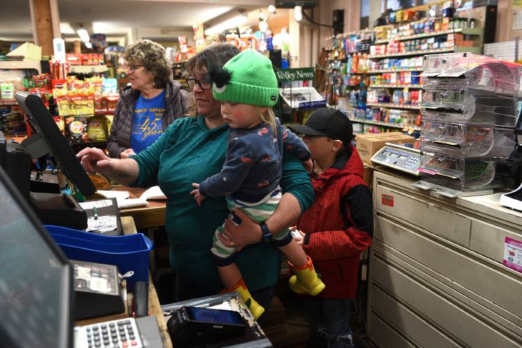 While running the cash register, Chrissy Jamieson watches after 18-month-old Waylon Johnson, and Wilder Johnson, 7, of Strafford, Vt., while their father picks up a few groceries at Coburns' General Store in South Strafford on Wednesday, Jan. 24, 2024. Jamieson's family has owned the store since 1977 and are looking for a new owner. Customer Janet Hardy, of Strafford, is at the register checking out her groceries. (Valley News - Jennifer Hauck) Copyright Valley News. May not be reprinted or used online without permission. Send requests to permission@vnews.com.