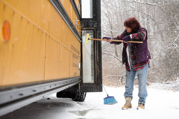 Carlene Masciarelli, of Canaan, cleans the lights and windows of her bus in West Lebanon, N.H., between shuttle runs of students from Mascoma Valley Regional High School and Hartford Area Career and Technical Center on Thursday, Jan. 12, 2023. (Valley News - James M. Patterson) Copyright Valley News. May not be reprinted or used online without permission. Send requests to permission@vnews.com.