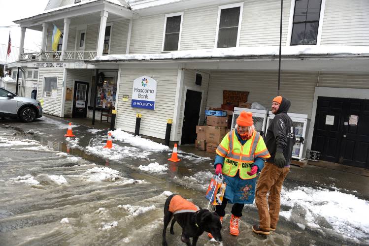 After giving Roz Finn a hug goodbye, Neal MacPhail, of Strafford, Vt., goes back to using his roof rake to clean the roof at Coburns' General Store in South Strafford, Vt., on Friday, Jan. 26, 2024. After doing a little shopping, Roz Finn walks back to her home with her dog Tashi. When at the store earlier, owners of the store asked him if he happened to have a roof rake they could use to clean off the snowy roof at the store. MacPhail returned with the rake and cleared the snow away himself. (Valley News - Jennifer Hauck) Copyright Valley News. May not be reprinted or used online without permission. Send requests to permission@vnews.com.