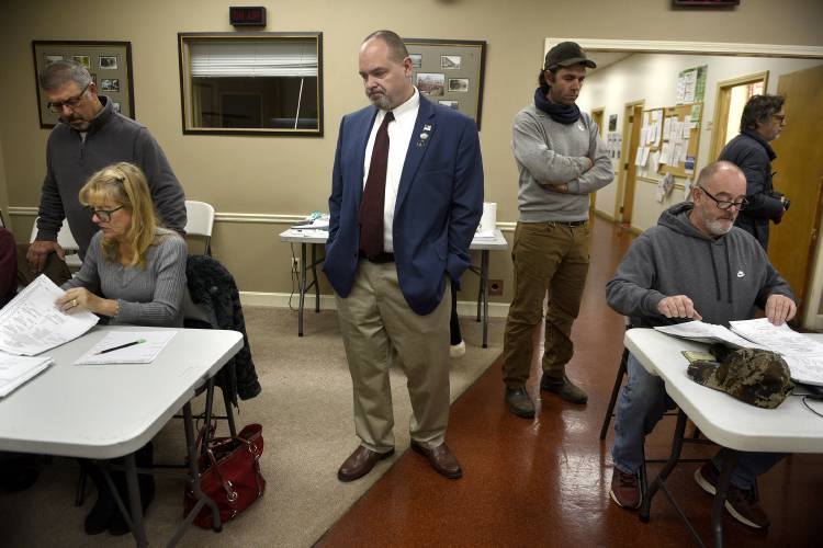 Standing between two tables, Claremont City Councilor Jonathan Stone, left, watches votes being counted with incoming city councilor Jonathan Hayden at City Hall in Claremont, N.H. on Tuesday, Nov. 14, 2023. Hayden defeated Stone last week for the Ward III seat 247-241. Stone asked for a recount of the results, which did not change. Assistant Mayor Debbie Matteau and Ward III Moderator Bill Blewitt, right, count votes as Keith Raymond observes.(Valley News - Jennifer Hauck) Copyright Valley News. May not be reprinted or used online without permission. Send requests to permission@vnews.com.