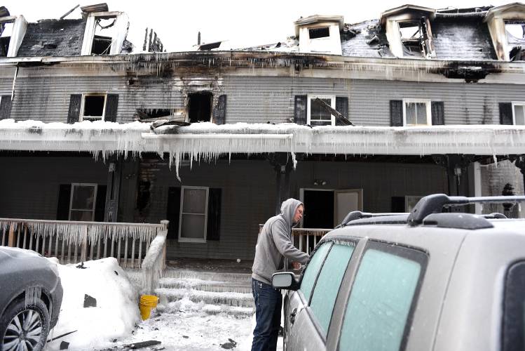 Brian Larson, of Newport, N.H. tries to break through ice on Andrew Cloutier's car on Jan. 19, 2024, after a structure fire destroyed Cloutier's apartment on Thursday night. The fire destroyed the 14-unit building, which was built in 1880 and was used as a boarding house for summer visitors to the area in the past. (Valley News - Jennifer Hauck) Copyright Valley News. May not be reprinted or used online without permission. Send requests to permission@vnews.com.