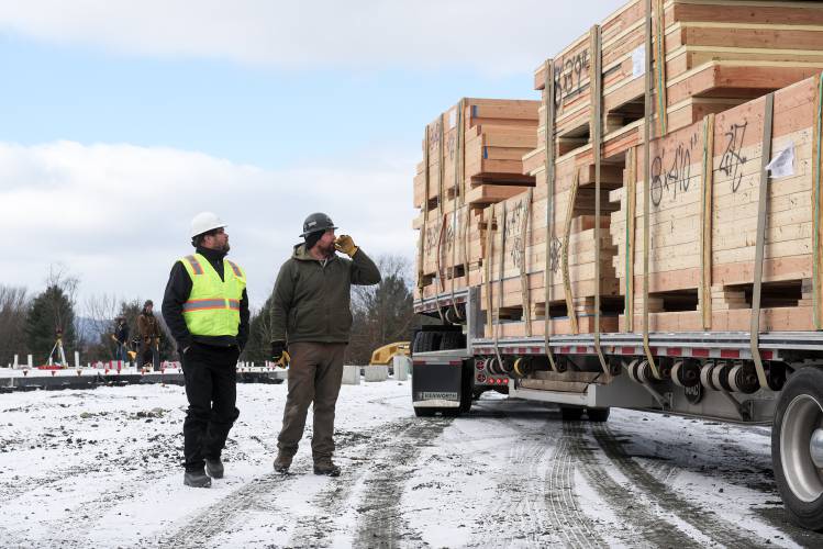 Michael Wright, project superintendent for H.P. Cummings, left, and Jacob Boule, co-owner of framing contractor Boule and Sons, right, look over a delivery of prefabricated wall panels at the site of the future MyPlace hotel in Randolph Center, Vt., on Monday, Nov. 20, 2023. Wright said he expects to have the walls up and roof on the building by mid-January. (Valley News - James M. Patterson) Copyright Valley News. May not be reprinted or used online without permission. Send requests to permission@vnews.com.