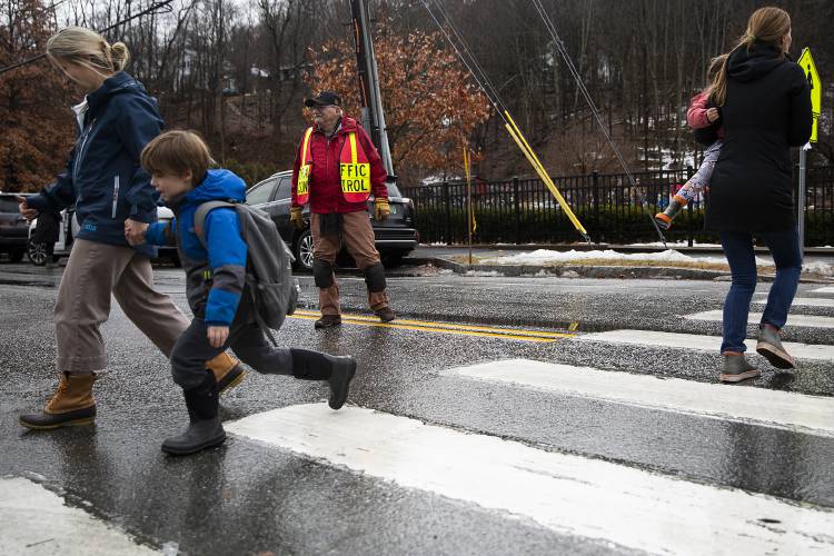 Crossing guard Wes Hennig, center, directs traffic during an early dismissal at Woodstock Elementary School in Woodstock, Vt., on Monday, Dec. 18, 2023. Mountain Views, Windsor Southeast and White River Valley supervisory unions all sent students home early as continued rainfall and swelling rivers caused flooding concerns. (Valley News / Report For America - Alex Driehaus) Copyright Valley News. May not be reprinted or used online without permission. Send requests to permission@vnews.com.