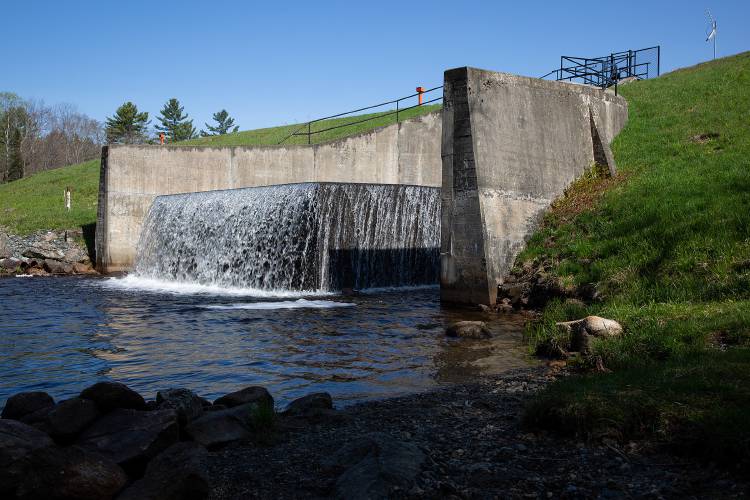 Water flows through a 31-foot dam at Goose Pond in Canaan, N.H., on Thursday, May 12, 2022. The dam, which was built in 1918, is in need of repair and the New Hampshire Department of Environmental Services plans to drain the lake 22 feet this winter in order to widen and stabilize the structure. (Valley News / Report For America - Alex Driehaus) Copyright Valley News. May not be reprinted or used online without permission. Send requests to permission@vnews.com.