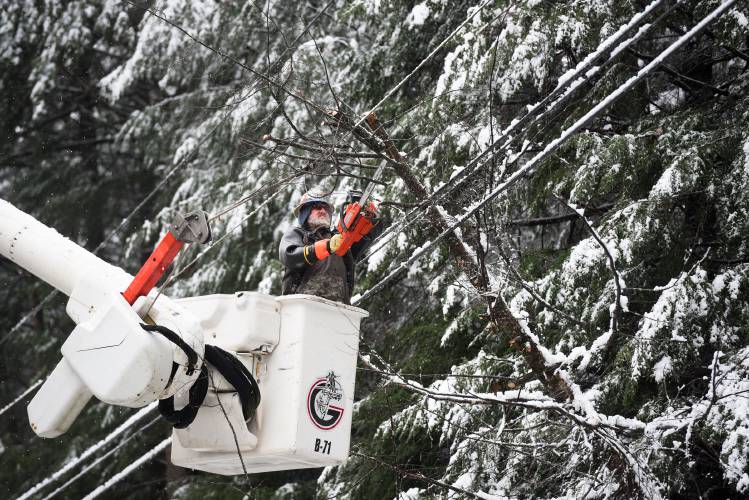 Chris Sentance, an electrical line worker with Grattan Line Construction, removes a tree that fell under heavy snow onto power lines in Norwich, Vt., on Monday, Dec. 4, 2023. At the mid-morning peak of the outages Green Mountain Power had more than 4,000 customers without power. (Valley News - James M. Patterson) Copyright Valley News. May not be reprinted or used online without permission. Send requests to permission@vnews.com.
