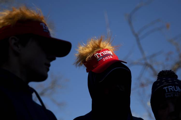 From left, Konner Gregory, Dale Rickert and Janet Rickert, all of Springfield, Vt., don Trump-themed headgear while waiting in line to enter a campaign rally for former President Donald Trump at Stevens High School in Claremont, N.H., on Saturday, Nov. 11, 2023. Gregory, 18, will be voting in his first Presidential election in 2024. (Valley News / Report For America - Alex Driehaus) Copyright Valley News. May not be reprinted or used online without permission. Send requests to permission@vnews.com.