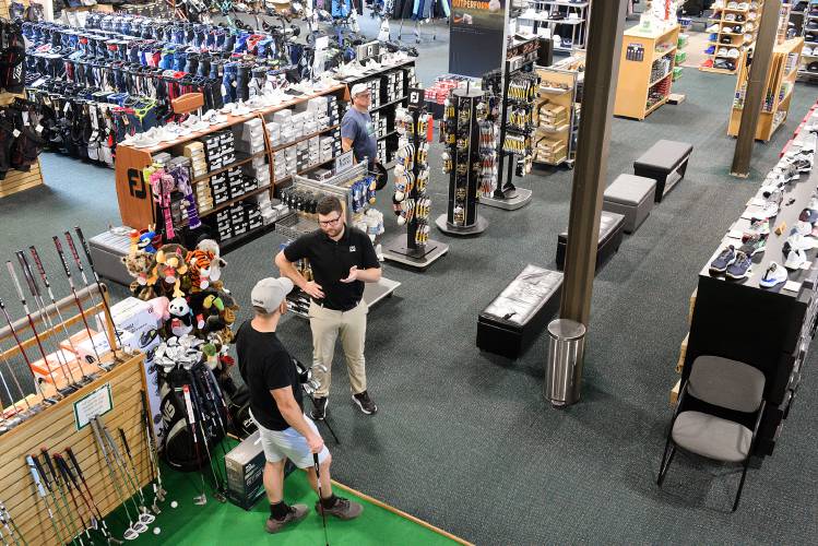 Ben Peters, assistant manager at Golf and Ski Warehouse, second from left, talks with Anthony Casale, of Lebanon, left, as Jeff Jones, of Milton, Vt., back, browses the aisles the store in West Lebanon, N.H., on Friday, June 23, 2023. The store was sold Worldwide Golf Shops, and Peters said he expects continuity in the store's original name and offerings. 